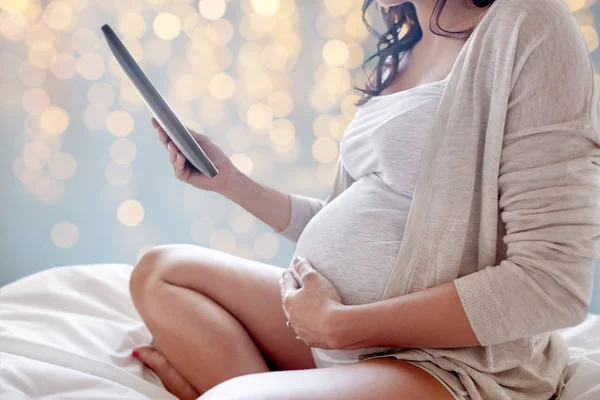 Närbild av gravid kvinna med TabletPC i sängen — Stockfoto