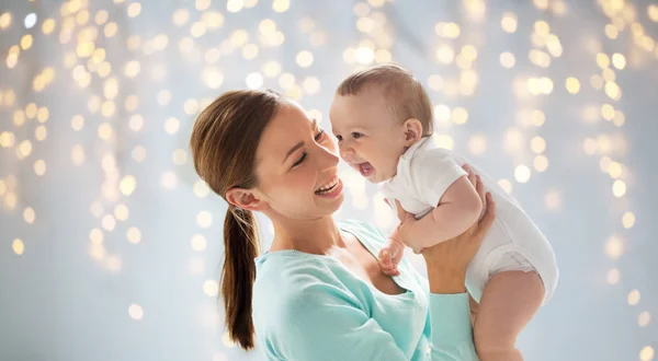 Glückliche junge Mutter mit kleinem Baby über Lichtern — Stockfoto