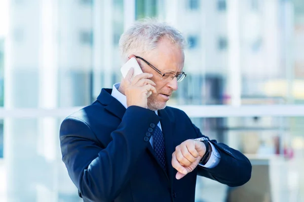 Hombre de negocios senior que llama en el teléfono inteligente en la ciudad — Foto de Stock