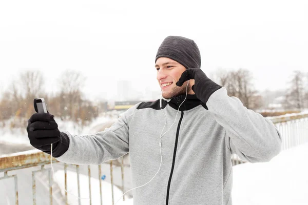 Lycklig man med hörlurar och smartphone på vintern — Stockfoto