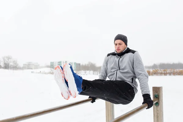 Młody człowiek, ćwiczenia na poręczach w zimie — Zdjęcie stockowe