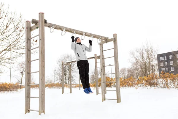 Jonge man uitoefenen op horizontale balk in de winter — Stockfoto