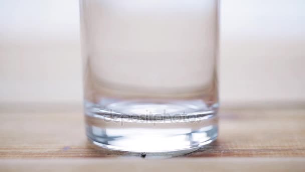 Ручной налив молока в пустой стакан на деревянный стол — стоковое видео