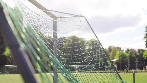 Мяч летит в футбольную сетку ворот на поле — стоковое видео