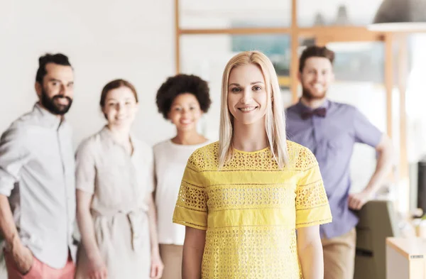 Feliz joven mujer sobre creativo equipo en la oficina — Foto de Stock