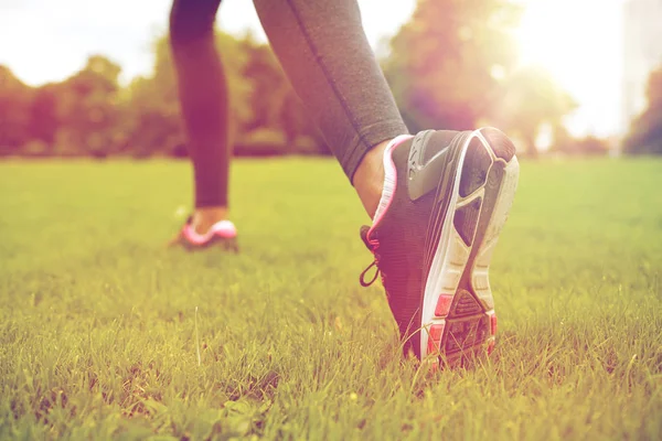 Primer plano de ejercicio piernas de mujer en la hierba en el parque — Foto de Stock