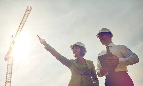Constructores felices en sombreros con tableta pc al aire libre —  Fotos de Stock
