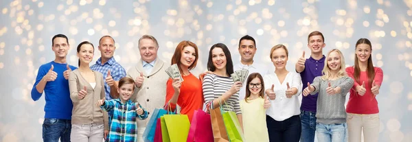 Glada människor med shoppingväskor och pengar — Stockfoto