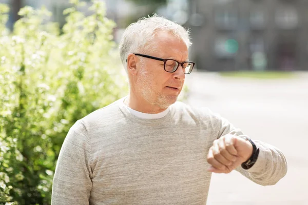 Senior man controleert de tijd op zijn polshorloge — Stockfoto