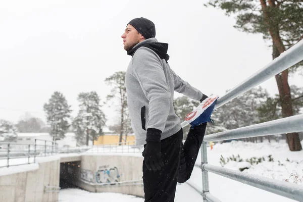 스포츠 겨울에 울타리에 다리를 스트레칭 하는 남자 — 스톡 사진