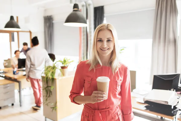 Femme créative heureuse avec tasse de café au bureau — Photo