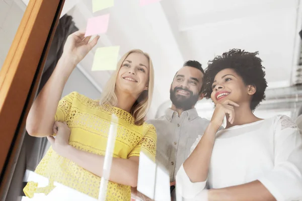 Lyckliga kreativa team skriva på klistermärken på kontor — Stockfoto