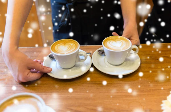 Close up de mãos com arte latte em xícara de café — Fotografia de Stock