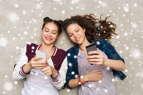 Chicas adolescentes felices tumbadas en el suelo con teléfono inteligente —  Fotos de Stock