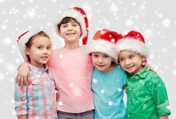 Niños pequeños y felices en sombreros de santa abrazo —  Fotos de Stock