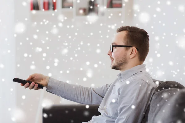 Uomo sorridente con telecomando tv a casa — Foto Stock