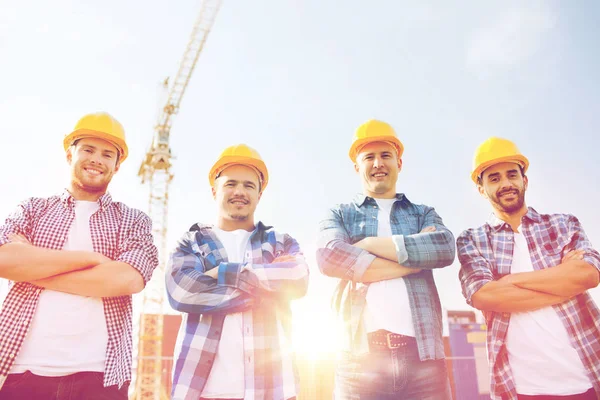 Groep van lachende bouwers in hardhats in openlucht — Stockfoto