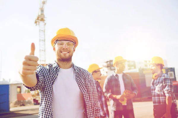 Grupa budowniczych uśmiechający się w hardhats na zewnątrz — Zdjęcie stockowe