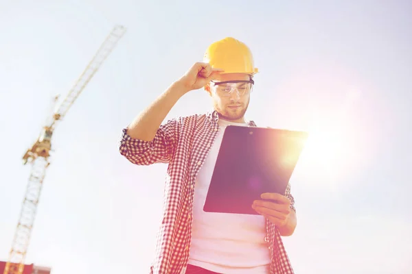 Builder in hardhat with clipboard outdoors — Stock Photo, Image