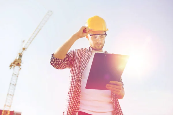 Construtor em hardhat com prancheta ao ar livre — Fotografia de Stock