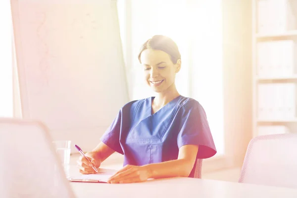 Счастливая женщина врач или медсестра, пишущая в буфер обмена — стоковое фото