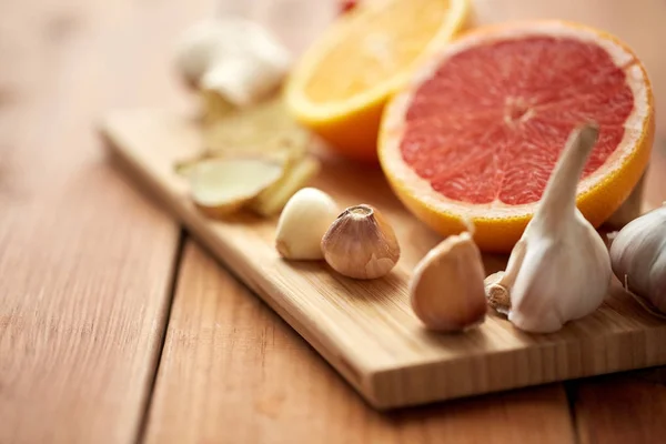 Garlic, grapefruit, ginger, and orange on board — Stock Photo, Image