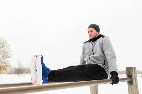 Jovem exercitando-se em barras paralelas no inverno — Fotografia de Stock