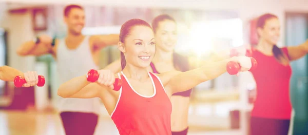 Grupo de personas sonrientes haciendo ejercicio con pesas — Foto de Stock