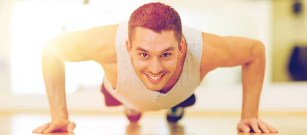 Hombre sonriente haciendo flexiones en el gimnasio — Foto de Stock