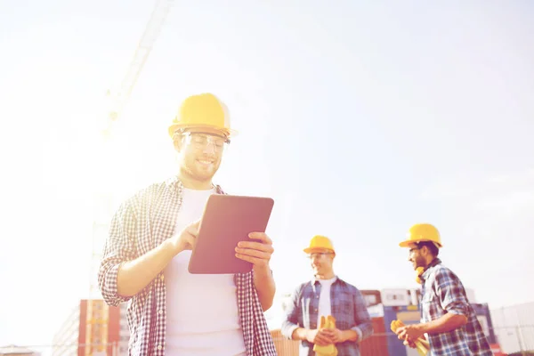 Construtores sorridentes em hardhats com tablet pc — Fotografia de Stock
