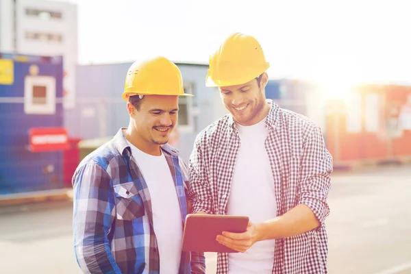 Constructores sonrientes en sombreros con tablet pc — Foto de Stock