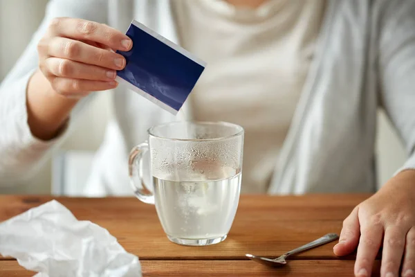 Woman pouring medication into cup of water — Stock Photo, Image