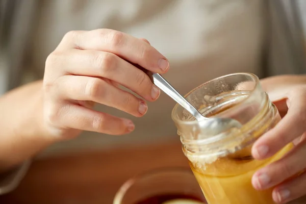 Menutup tangan wanita dengan toples madu dan sendok — Stok Foto