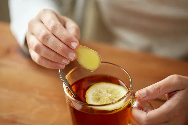 Gros plan de la femme ajoutant du gingembre au thé au citron — Photo