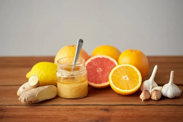 Madu, jeruk buah, jahe dan bawang putih di atas kayu — Stok Foto