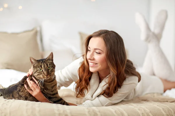 Щаслива молода жінка з кішкою лежить в ліжку вдома — стокове фото