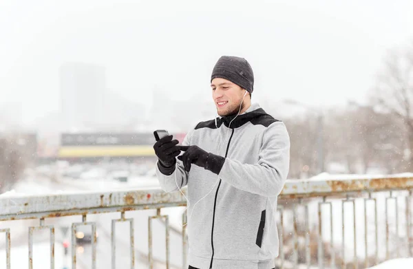 Lycklig man med hörlurar och smartphone på vintern — Stockfoto