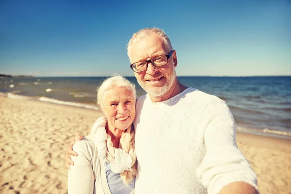 Senioren nemen van foto met selfie stick op strand — Stockfoto