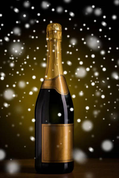 Garrafa de champanhe com etiqueta dourada sobre a neve — Fotografia de Stock