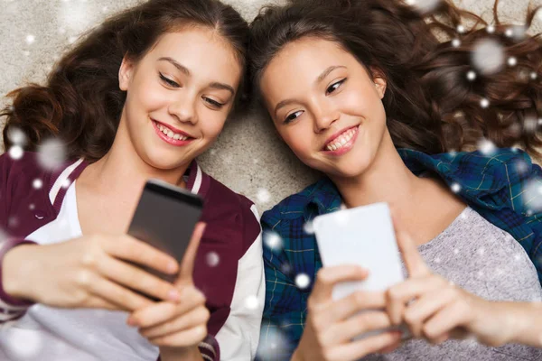 Gelukkig tienermeisjes, liggend op de vloer met smartphone — Stockfoto