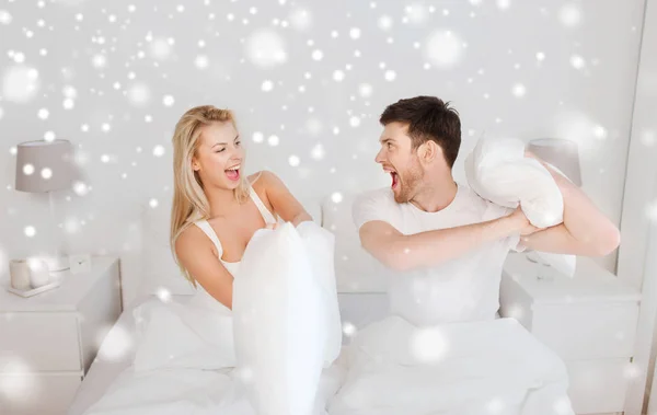 Feliz pareja teniendo almohada lucha en cama en casa — Foto de Stock