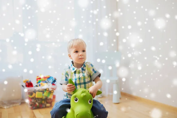 Fröhlicher kleiner Junge spielt zu Hause mit Aufsitzspielzeug — Stockfoto