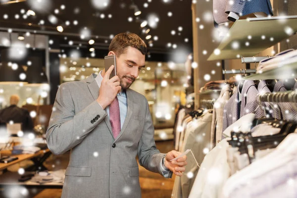 Šťastný muž volá na smartphone v obchodě s oděvy — Stock fotografie