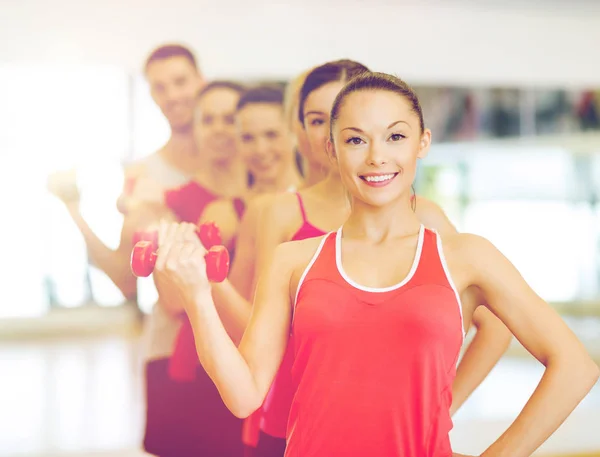 Grupp av leende människor med hantlar i gymmet — Stockfoto