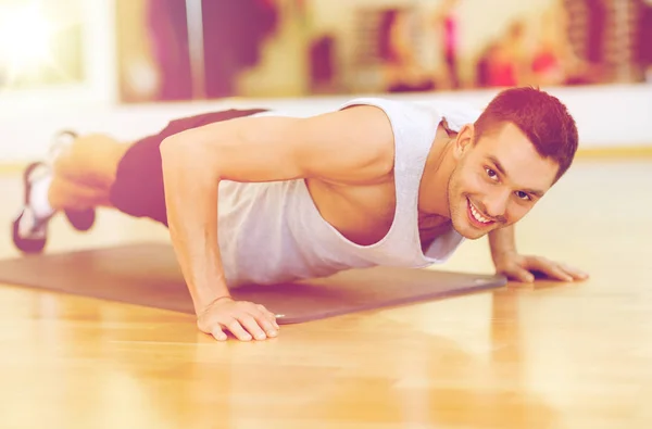 Uomo sorridente che fa flessioni in palestra — Foto Stock