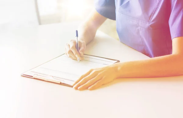 Primer plano de la escritura del médico o la enfermera al portapapeles —  Fotos de Stock