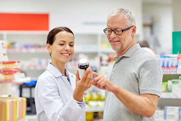 Apotekare visar läkemedel till äldre man på apotek — Stockfoto