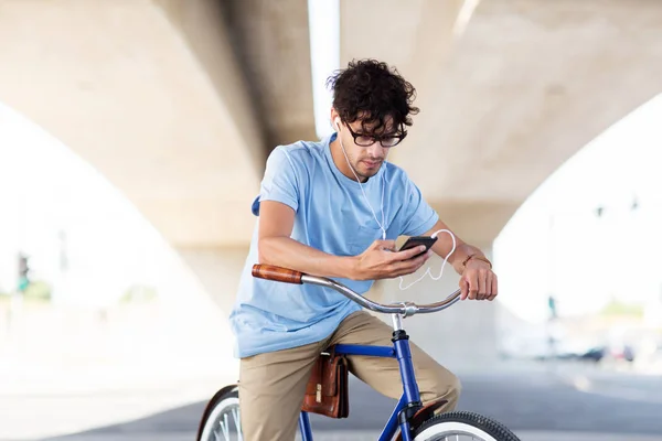 Hombre con smartphone y auriculares en bicicleta —  Fotos de Stock