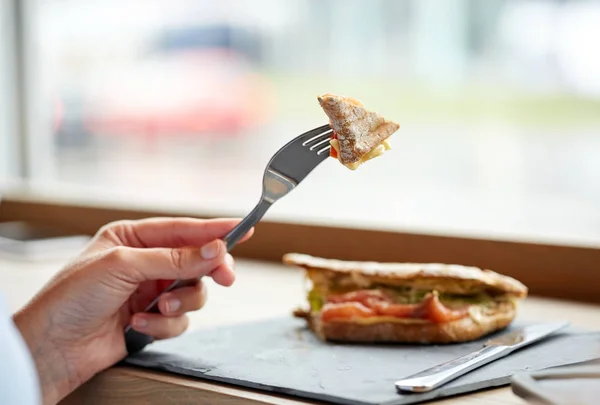 Frau isst Lachs-Panini-Sandwich im Restaurant — Stockfoto