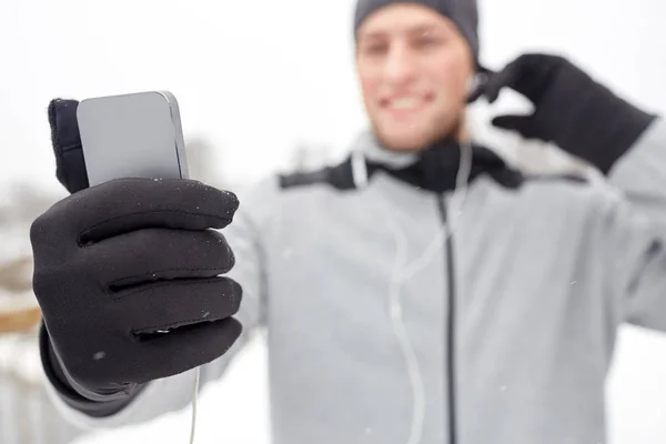 Lycklig man med hörlurar och smartphone på vintern — Stockfoto